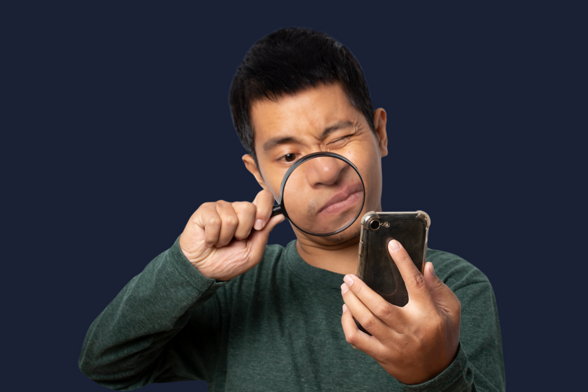 Homme avec une loupe qui regarde son téléphone mobile